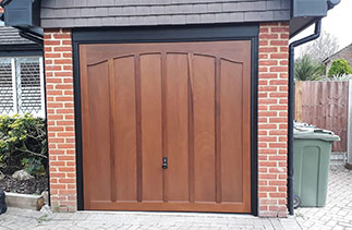 A Woodrite up and over timber garage door from the Somerset range in the Wasford style. Finished in Light Oak on a Dark board. With a Black steel frame and Black Ash pvc. Fitted in East Horsley. Surrey.