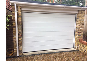 A Carteck 40mm insulated sectional garage door. In the Centre rib style. In a White wood grain textured finish. Fitted in Camberley. Surrey.