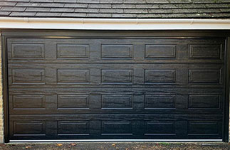 A Carteck 40mm insulated sectional garage door. In the Georgian style. In a Black wood grain finish. The Georgian style is only available in a wood grain textured finish. Fitted in Cobham. Surrey.