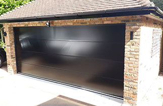 A Carteck 40mm insulated sectional garage door. In the Solid rib style. In a Black smooth finish. Fitted in Camberley. Surrey.