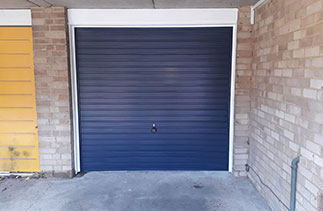 A Garador steel range up and over garage door in the Horizon style. In steel Blue colour with a White steel frame. Fitted in Camberley. Surrey.