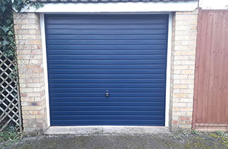 A Garador steel up and over garage door in the Horizon style in steel Blue colour with a White steel frame. Fitted in Yatley. Hampshire.