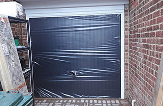 A Garador steel up and over garage range up and over garage door. In the Carlton style in Black with a White steel frame. With a Chrome effect handle. Fitted in Finchampstead. Berkshire. The protective wrapping was left on because there were on going building works.