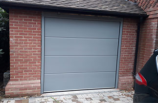 A Carteck Solid rib sectional garage door fitted within the opening. Finished in a colour match to Farrow and Ball Plummet Grey NR 272. Fitted in West Byfleet, near Woking, Surrey.