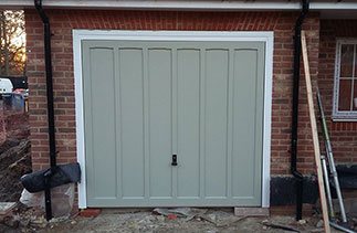 A Woodrite timber up and over garage door  finished in a colour match to Farrow and Ball French Grey with a white steel frame and chassis.