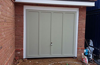 A Garador Grantham timber up and over garage door in a colour match to Farrow and Ball French Grey. Fitted with a white steel frame on retractable plus door gear with a Chrome effect handle. Fitted in Farnham, Surrey