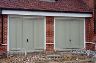 Two timber Churchill style garage doors in a colour match to Farrow & Ball French Grey. Fitted with white steel frames and white chassis to plot 5 in Hartley Wintney, Hampshire.
