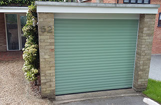 A Gliderol insulated, electronically operated Roller shutter Garage Door in Chartwell Green with white guides and a white 90 degree half top box. Fitted in Camberley, Surrey.