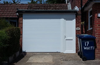 A Gliderol White insulated, electronically operated compact roller shutter garage door with a full internal box. Complete with a UPVC cladded timber divide and a White UPVC side door. Fitted in Haslemere, Surrey.