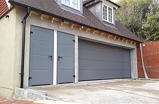 A Hormann LPU - 40 insulated sectional garage door with Two matching block framed side doors. The doors are in a smooth finish and finished in Ral 7005. The new style Hormann logo badge was removed to enhance the appearance of the garage door. Garage doors fitted in Guildford, Surrey.