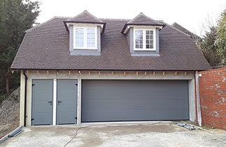 A Hormann LPU - 40 insulated sectional garage door with Two matching block framed side doors. The doors are in a smooth finish and finished in Ral 7005. The new style Hormann logo badge was removed to enhance the appearance of the garage door. Garage doors fitted in Guildford, Surrey.