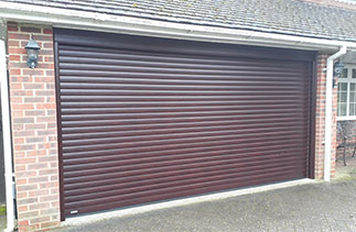 A Sws Seceuroglide Excel insulated, electronically operated Roller Shutter Garage Door in Mahogany with matching UPVC to cover the existing timber frame. Fitted in Camberley, Surrey.