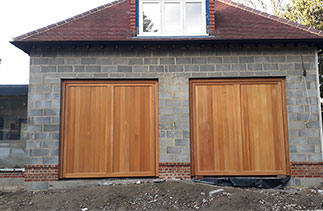 Two Woodrite Chalfont style Cedar wood up and over garage doors fitted with Cedar clad Hard wood timber frames. Doors are supplied in base coat Light Oak stain for on site finishing. Doors fitted in Worplesdon, Surrey.