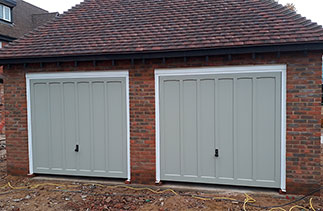 Two Woodrite Churchill style timber garage doors, fitted with white steel frames. On retractable plus door gear. Fitted in Winchfield, Hampshire.